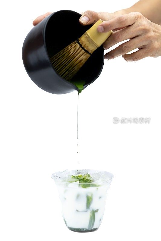 Hand pouring matcha into cup with ice and milk on a white background - process of making matcha tea